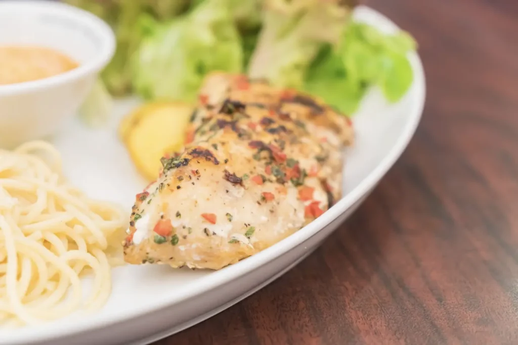 Baked thin chicken breasts with garlic and herbs on a white plate